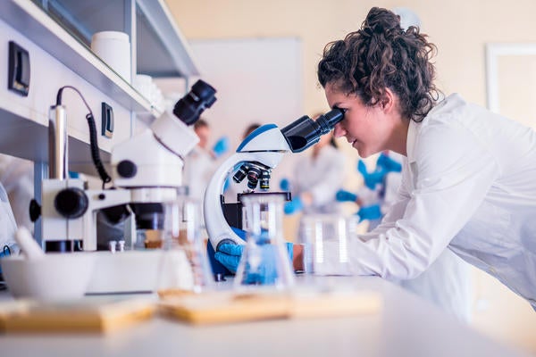 student in lab looking through microscope (c) iStock