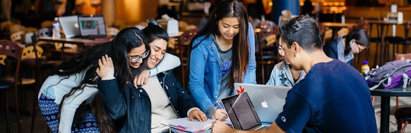 students at a table working and smiling (c) UCR